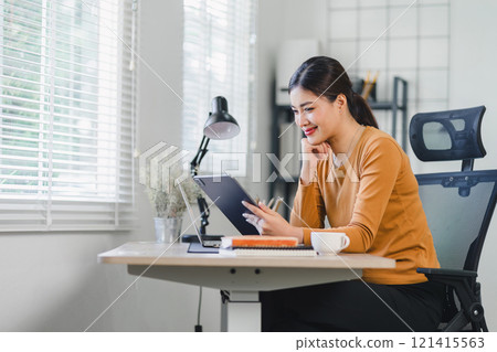 Confident Asian businesswoman smiling and using a digital tablet in a modern office setting, poised for productivity. Confident Asian businesswoman smiling and using a digital tablet in a modern office setting, poised for productivity. 121415563