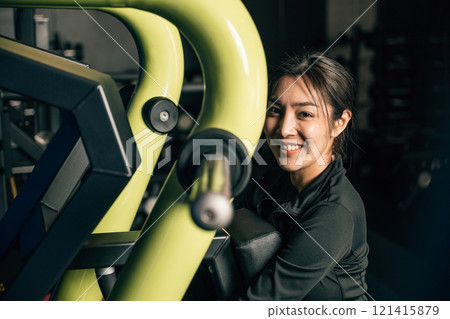 Portrait of beautiful Asian young woman performing squats on a gym machine, female working out with rowing machine at crossfit fitness, healthy lifestyle concept 121415879