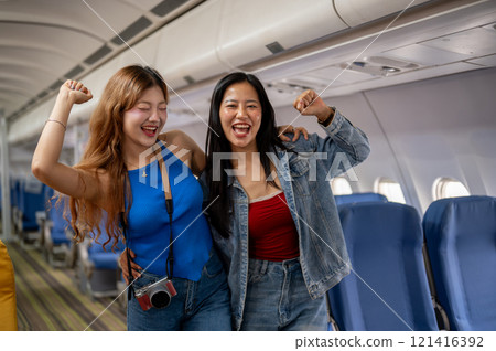 Two excited, joyful Asian female best friends stand in the aisle of a plane, traveling together. Two excited, joyful Asian female best friends stand in the aisle of a plane, traveling together. 121416392