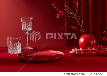 Red tone photography with luxury new year conceptual. Some blank tableware by ceramic and glass displayed on red table, next to some fruit jam and red flower vase Red tone photography with luxury new year conceptual. Some blank tableware by ceramic and glass displayed on red table, next to some fruit jam and red flower vase 121417220