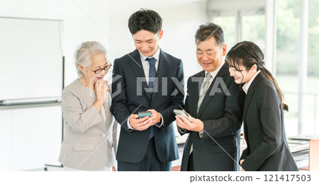 使用智慧型手機的老年人和年輕商人(家族管理、繼承人、企業繼承、繼承、出售、收購、代際更替) 使用智慧型手機的老年人和年輕商人(家族管理、繼承人、企業繼承、繼承、出售、收購、代際更替) 121417503
