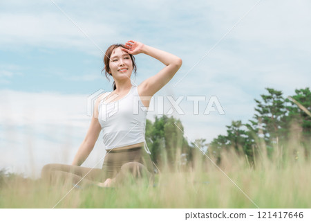 A woman doing yoga, stretching, pilates and body care in the grassland (healthcare, diet, health maintenance) 121417646