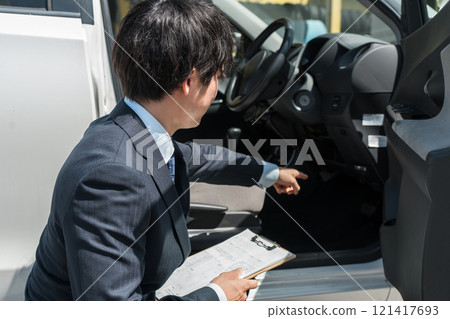 Salesman/appraiser using a checklist to assess and estimate a car Salesman/appraiser using a checklist to assess and estimate a car 121417693