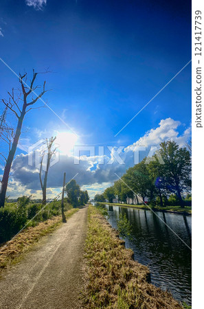 A Beautiful Scenic Pathway Running Alongside a Serene Canal Beneath a Bright Clear Sky A Beautiful Scenic Pathway Running Alongside a Serene Canal Beneath a Bright Clear Sky 121417739