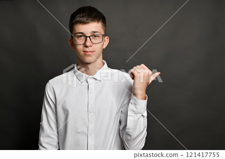 portrait of a guy with glasses. he points his thumb back at copy space. on a gray background. 121417755