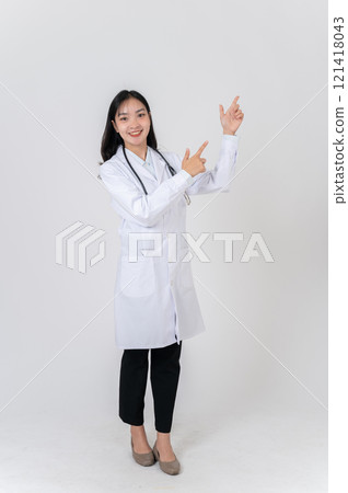 A positive Asian female doctor pointing to the side as if recommending an option, studio background. A positive Asian female doctor pointing to the side as if recommending an option, studio background. 121418043