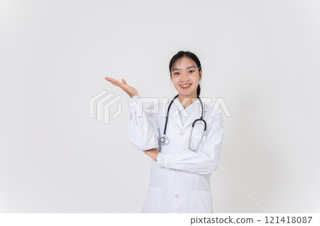 A female doctor smiling warmly and presenting with an open palm, as if recommending something. 121418087