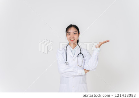 A female doctor smiling warmly and presenting with an open palm, as if recommending something. 121418088