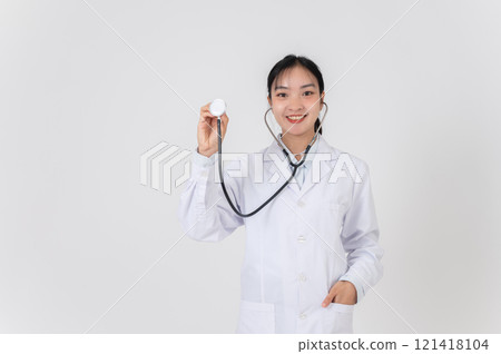 A doctor showing her stethoscope to the camera, standing against a white studio background. A doctor showing her stethoscope to the camera, standing against a white studio background. 121418104