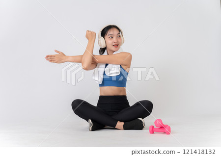 A sporty Asian woman in sportswear enjoying listening to music while stretching her arms. A sporty Asian woman in sportswear enjoying listening to music while stretching her arms. 121418132
