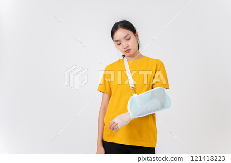A sad Asian woman with a broken arm wrapped in a plaster bandage, wearing a sling to support her arm A sad Asian woman with a broken arm wrapped in a plaster bandage, wearing a sling to support her arm 121418223