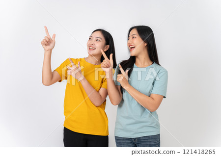 Two cheerful females pointing their finger upward at an empty space, recommending a special offer. 121418265