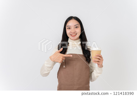 A smiling Asian female barista or cafe waitress pointing her finger at a hot drink cup in her hand. 121418390