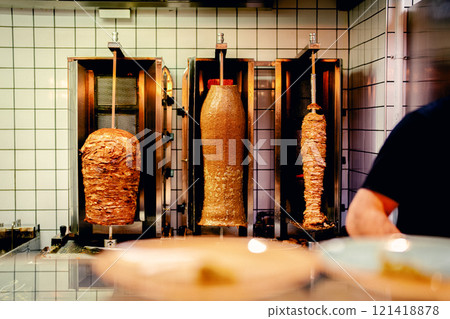 Rotating kebabs being cooked in a restaurant kitchen 121418878
