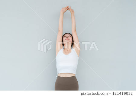 A woman in yoga wear or sportswear stretching, taking a deep breath, and refreshing 121419032
