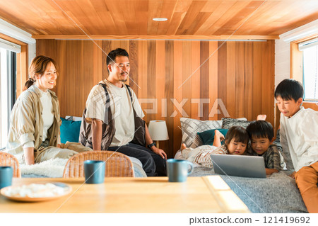 Family using a computer on a family trip during summer vacation (glamping, villa, cottage, log house) Family using a computer on a family trip during summer vacation (glamping, villa, cottage, log house) 121419692