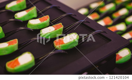 Platter of gourmet appetizers featuring pieces of salmon and cream cheese wrapped in a green wrap Platter of gourmet appetizers featuring pieces of salmon and cream cheese wrapped in a green wrap 121420104