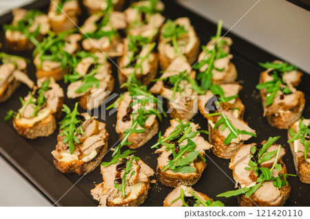 Gourmet bruschetta appetizers featuring slices of bread topped with meat, arugula Gourmet bruschetta appetizers featuring slices of bread topped with meat, arugula 121420110