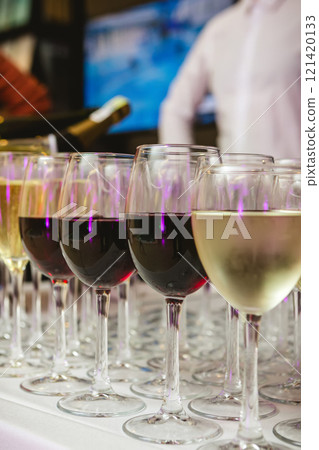 A beautifully arranged collection of wine glasses filled with red and white wines, set on a white tablecloth 121420133