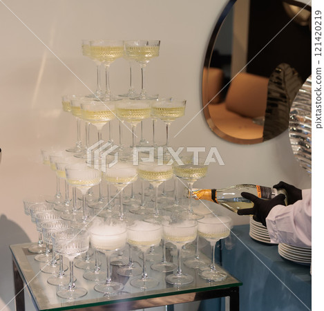 Towering pyramid of champagne glasses filled with bubbly Towering pyramid of champagne glasses filled with bubbly 121420219