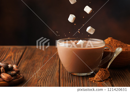 marshmallows falling in hot chocolate in glass cup on table 121420631
