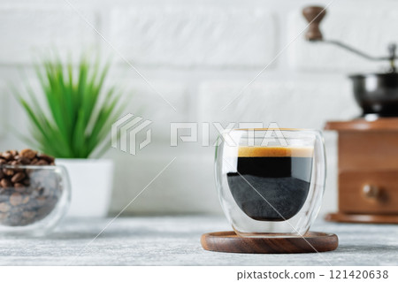 espresso in glass cup on table on white brick wall background 121420638