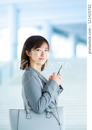 A woman in a suit going to work, an office lady holding a smartphone A woman in a suit going to work, an office lady holding a smartphone 121420782