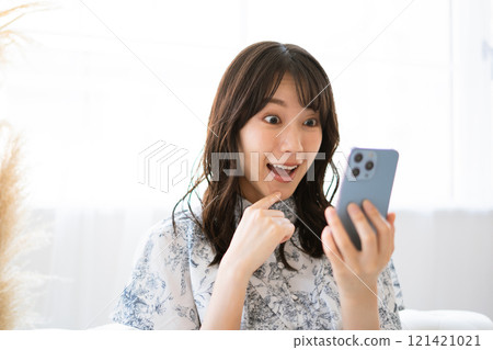 拿著智慧型手機的長黑髮的年輕女子 拿著智慧型手機的長黑髮的年輕女子 121421021