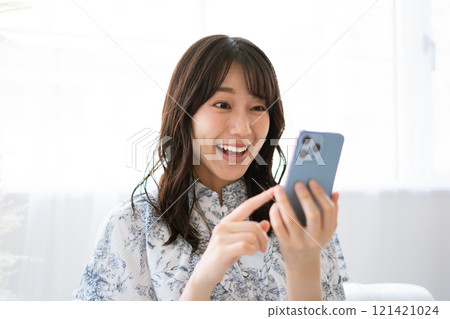A young woman with long black hair holding a smartphone A young woman with long black hair holding a smartphone 121421024