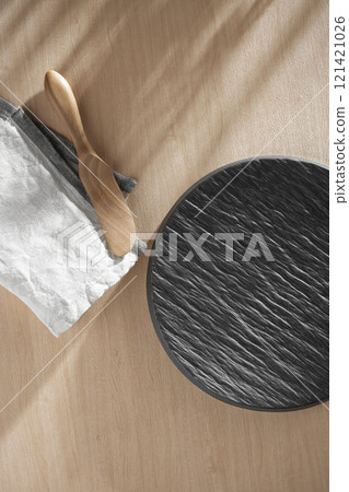 Various tableware on a soft wood-toned table background with sunlight shining through. 121421026