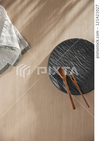 Various tableware on a soft wood-toned table background with sunlight shining through. Various tableware on a soft wood-toned table background with sunlight shining through. 121421027