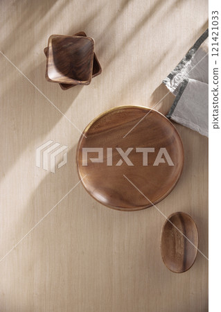 Various tableware on a soft wood-toned table background with sunlight shining through. Various tableware on a soft wood-toned table background with sunlight shining through. 121421033