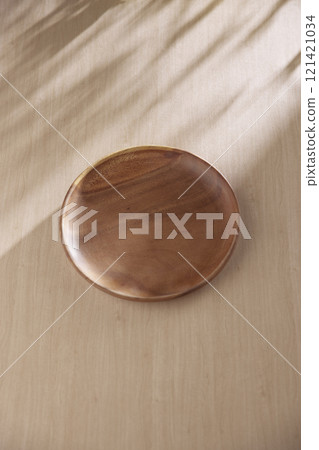 Various tableware on a soft wood-toned table background with sunlight shining through. Various tableware on a soft wood-toned table background with sunlight shining through. 121421034