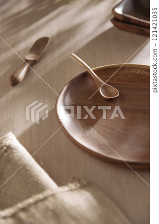 Various tableware on a soft wood-toned table background with sunlight shining through. 121421035
