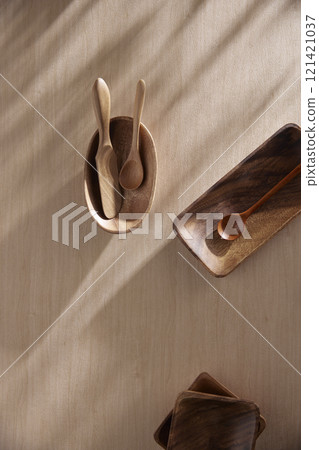 Various tableware on a soft wood-toned table background with sunlight shining through. Various tableware on a soft wood-toned table background with sunlight shining through. 121421037