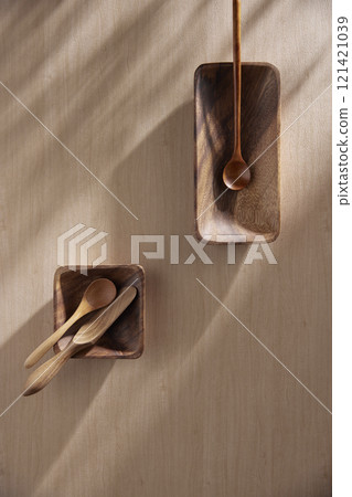 Various tableware on a soft wood-toned table background with sunlight shining through. 121421039