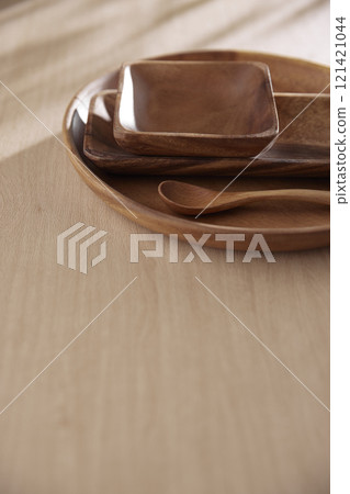 Various tableware on a soft wood-toned table background with sunlight shining through. 121421044