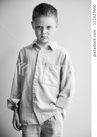 Portrait of young sad boy keeping hand in pocket, looking to the camera. Serious kid in casual clothes posing on white background. Black and white image. 121423600