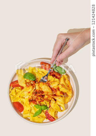 Hand holding fork with tagliatelle or pappardelle pasta with tomato sauce, basil and parmesan cheese Hand holding fork with tagliatelle or pappardelle pasta with tomato sauce, basil and parmesan cheese 121424828