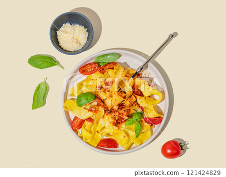 Tagliatelle or pappardelle pasta with tomato sauce, basil and parmesan cheese in a plate with fork Tagliatelle or pappardelle pasta with tomato sauce, basil and parmesan cheese in a plate with fork 121424829