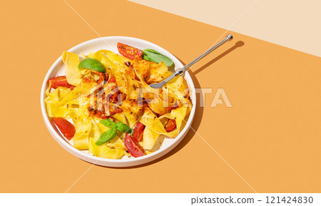 Tagliatelle or pappardelle pasta with tomato sauce, basil and parmesan cheese in a plate with fork Tagliatelle or pappardelle pasta with tomato sauce, basil and parmesan cheese in a plate with fork 121424830