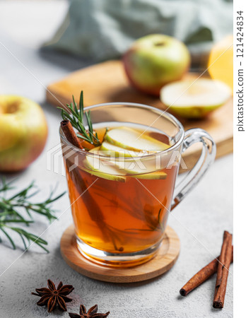 Homemade apple punch with apples, cinnamon and rosemary in a cup on a light background Homemade apple punch with apples, cinnamon and rosemary in a cup on a light background 121424834