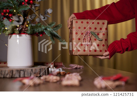 female hands holding Christmas gift box at home, New Year's Eve 121425731