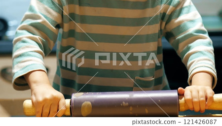 A little girl makes cookies at home using the rolling pin 121426087