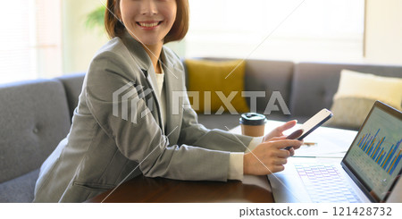 Indoor portrait of a woman holding a smartphone Indoor portrait of a woman holding a smartphone 121428732