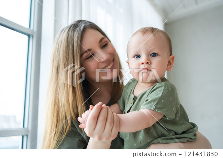 Happy family at home. Mother holding little toddler child daughter. Mom and baby girl relax playing having fun together at home. Mother hugging kissing baby with love care. Mom of breast feeding baby 121431830