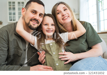 Happy family at home. Mother father children daughter relaxing on sofa indoor. Mom dad parents kid girl relax playing hugging having fun together. Family smiling laughing enjoying tender moment 121431832
