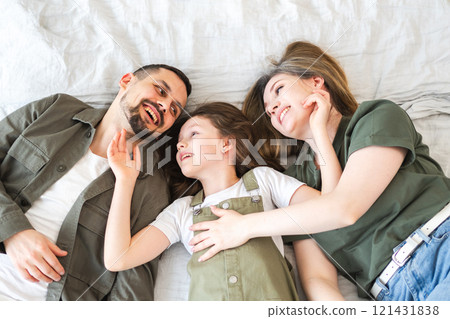 Happy family at home. Mother father children daughter relaxing in bed at home indoor. Mom dad parents kid girl relax playing hugging having fun together. Family smiling laughing enjoying tender moment Happy family at home. Mother father children daughter relaxing in bed at home indoor. Mom dad parents kid girl relax playing hugging having fun together. Family smiling laughing enjoying tender moment 121431838