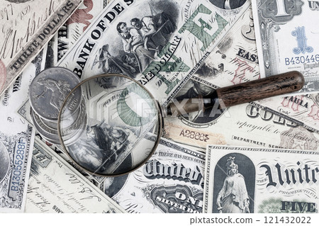 Retro vintage US greenback banknotes and silver certificates with silver dollar coins and magnifying glass Retro vintage US greenback banknotes and silver certificates with silver dollar coins and magnifying glass 121432022