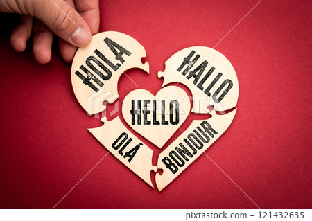Hello in different languages. Wooden puzzle in the shape of a heart on a red background Hello in different languages. Wooden puzzle in the shape of a heart on a red background 121432635